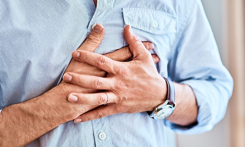 Chest pains are never a good sign. Shot of a unrecognizable man holding his chest in discomfort due to pain at home during the day.